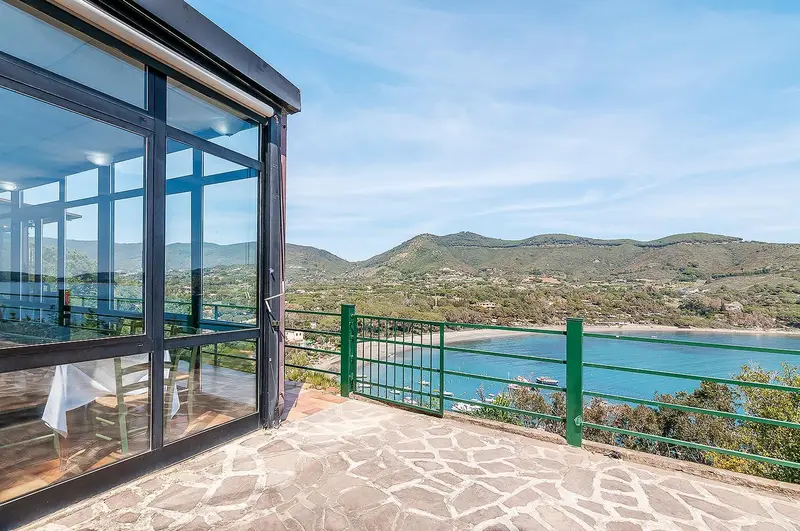 Terrasse pavée donnant sur une vue panoramique de la mer et des collines.