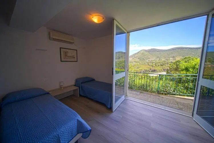 Une chambre lumineuse donne sur un paysage montagneux verdoyant.