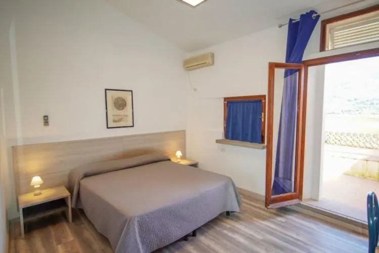 Une chambre lumineuse avec un lit et un accès à une terrasse.
