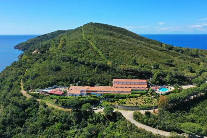 Vue aérienne d'un complexe hôtelier sur une colline verdoyante surplombant la mer.