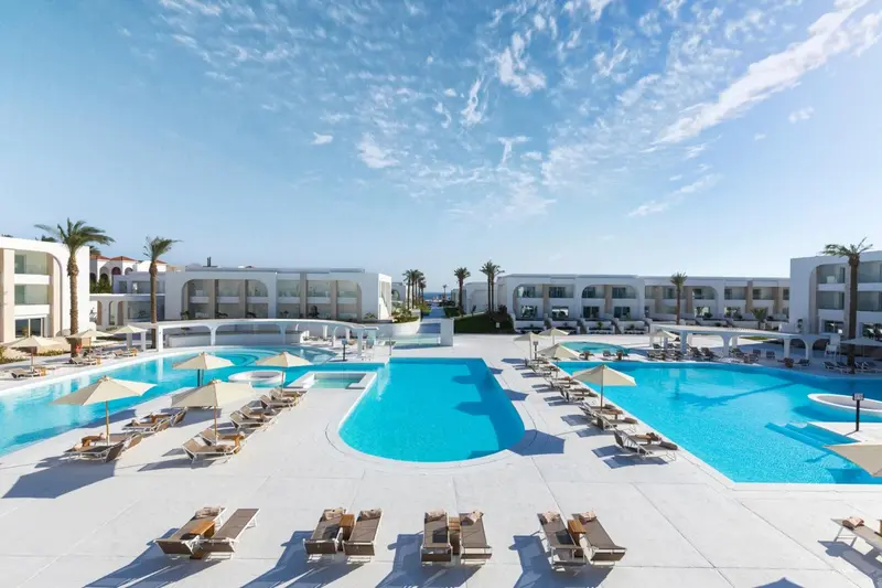 Vue aérienne d'un complexe hôtelier avec plusieurs piscines et des transats.