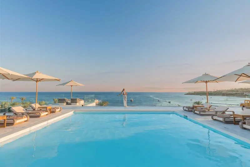 Une piscine à débordement offre une vue sur la mer et le ciel au coucher du soleil.