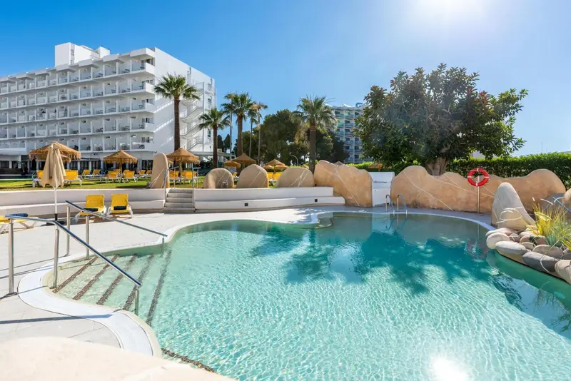 Piscine d'hôtel avec transats et végétation luxuriante en arrière-plan.