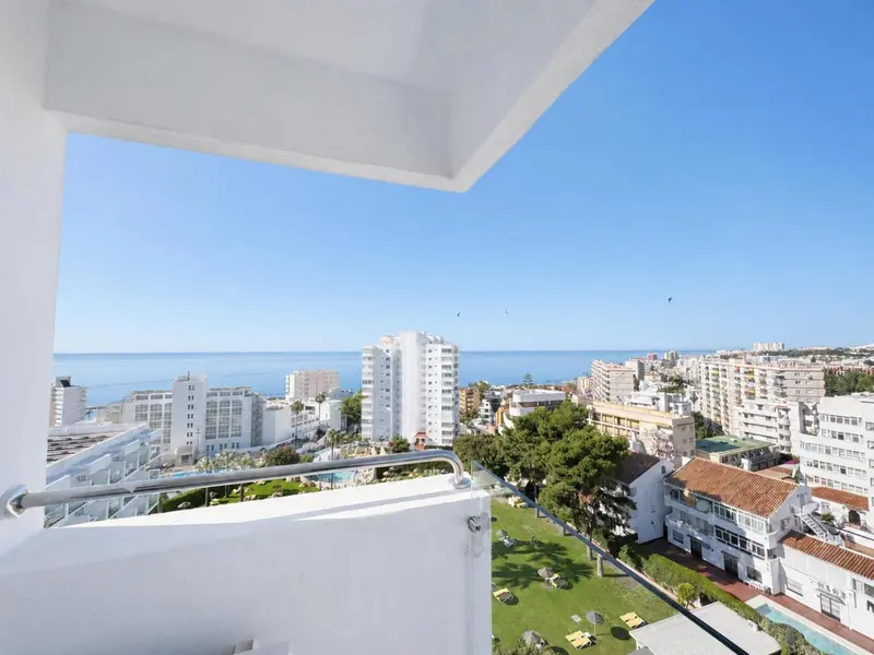 Vue dégagée sur la ville et la mer depuis un balcon.