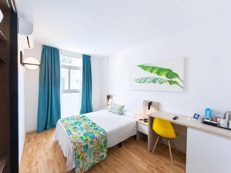 Une chambre lumineuse avec un lit simple et un bureau.