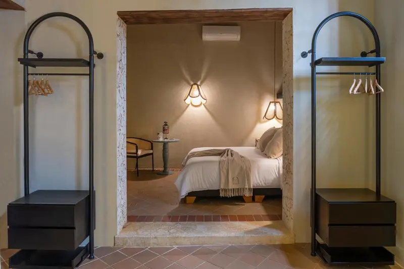 Une chambre lumineuse avec un lit fait et des patères en métal.