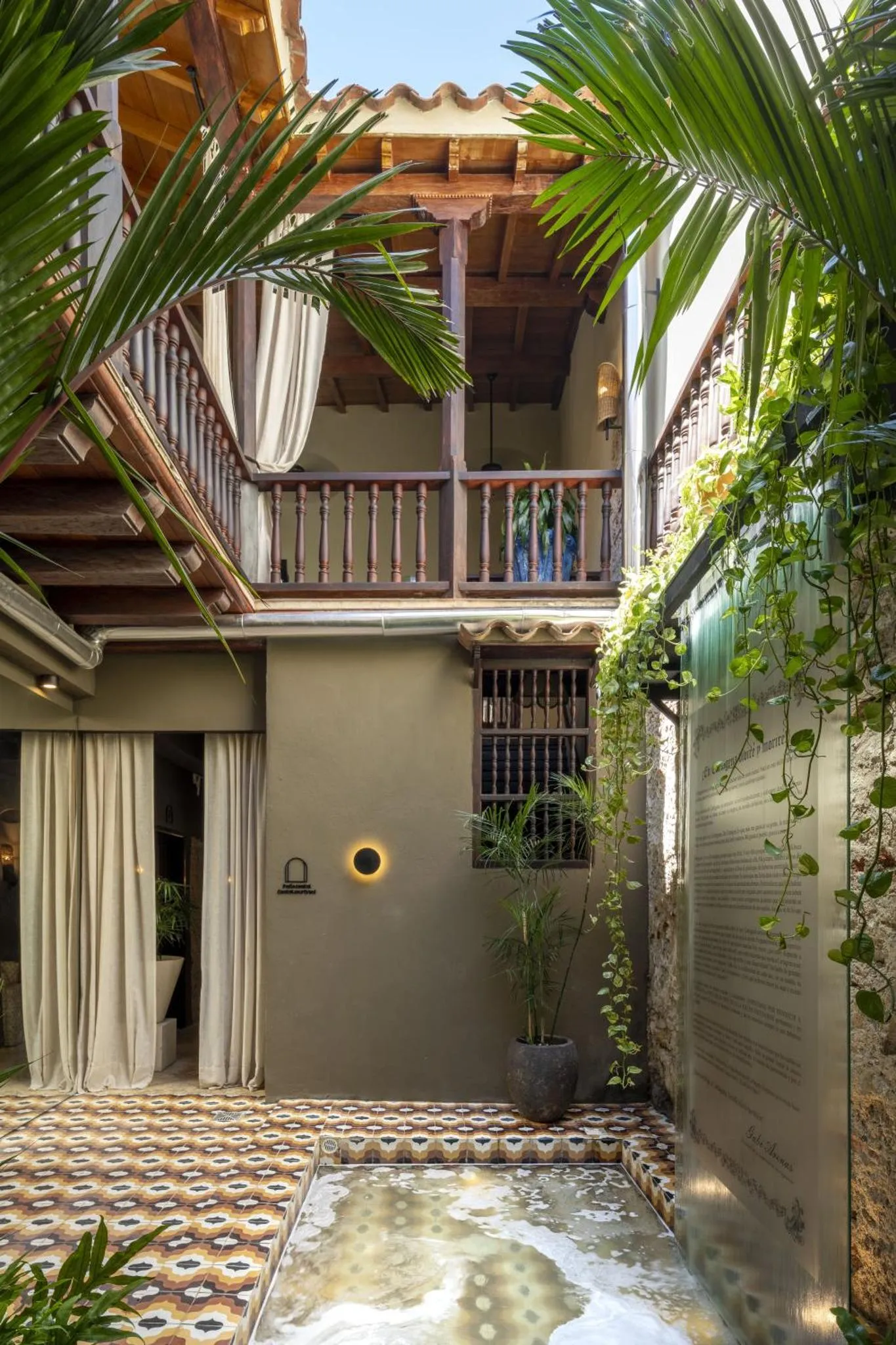 Une cour intérieure ombragée avec une fontaine et des plantes tropicales.