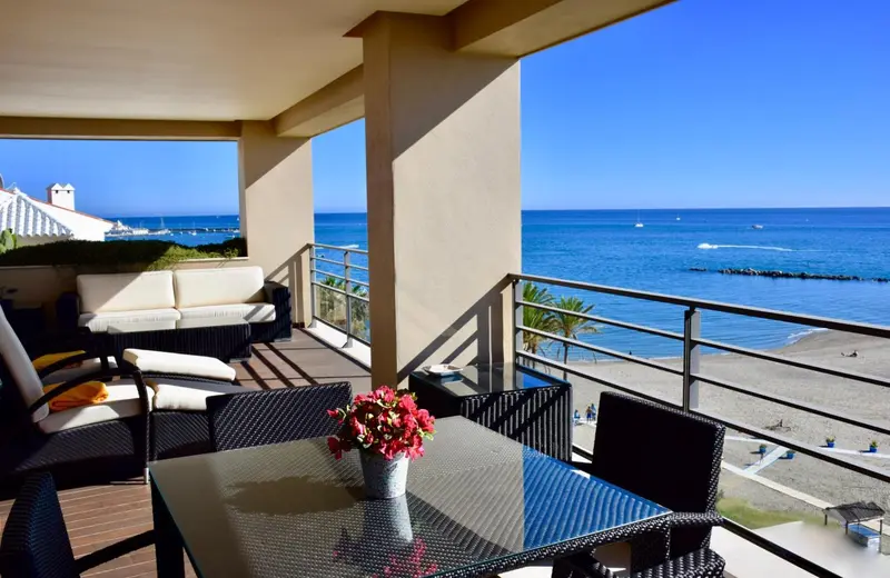Terrasse aménagée avec salon et table donnant sur la mer.