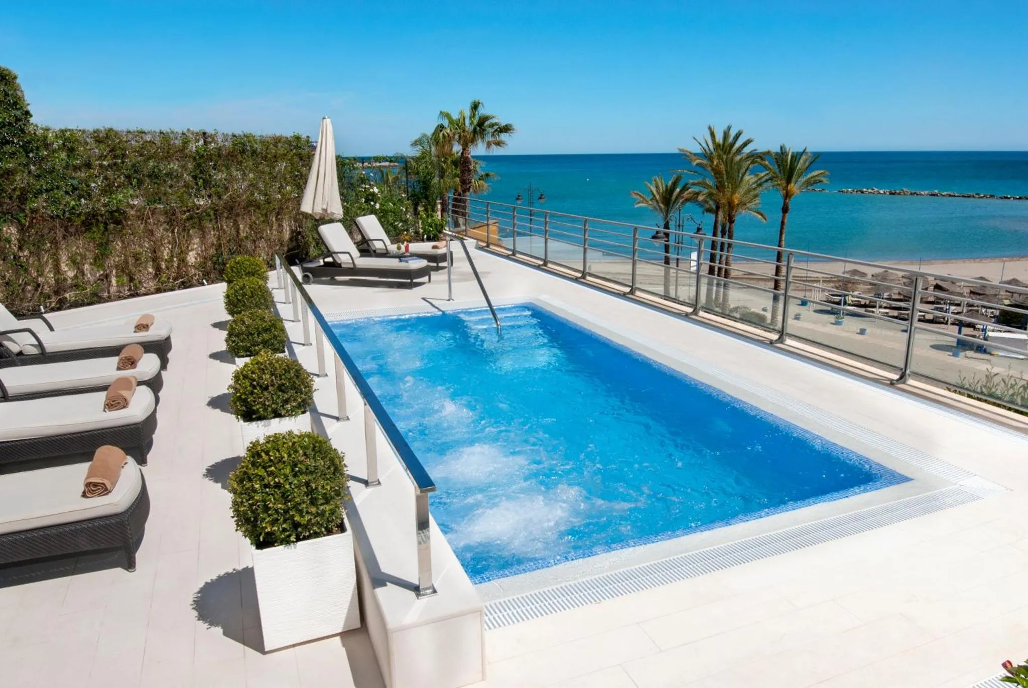 Terrasse avec piscine et chaises longues face à la mer.