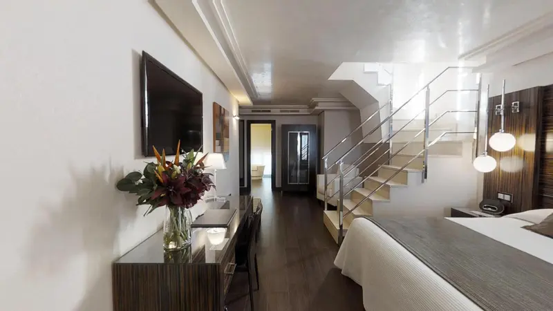 Une chambre spacieuse avec un lit et un escalier menant à une mezzanine.