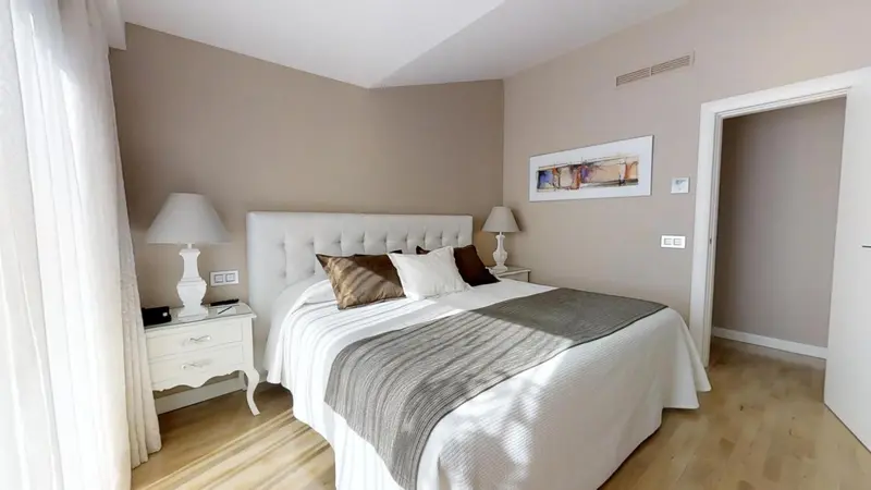 Une chambre lumineuse avec un grand lit et une décoration sobre.