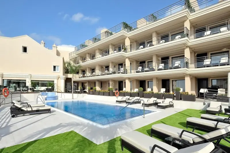 Vue d'un bâtiment beige avec des balcons et une piscine en contrebas.