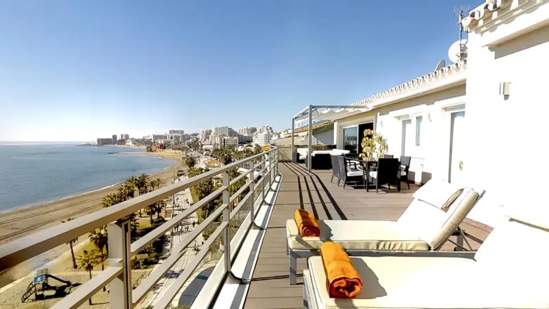 Terrasse avec transats et vue sur la mer et la ville.