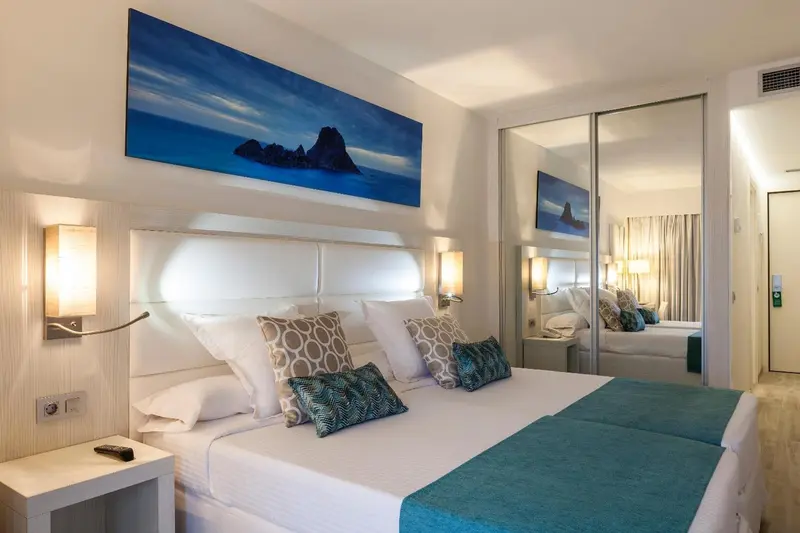 Chambre lumineuse avec un grand lit et une décoration moderne.