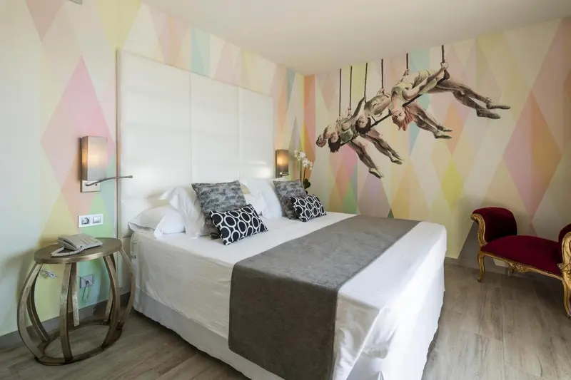 Une chambre lumineuse avec un grand lit et un mur décoré d'une fresque colorée.