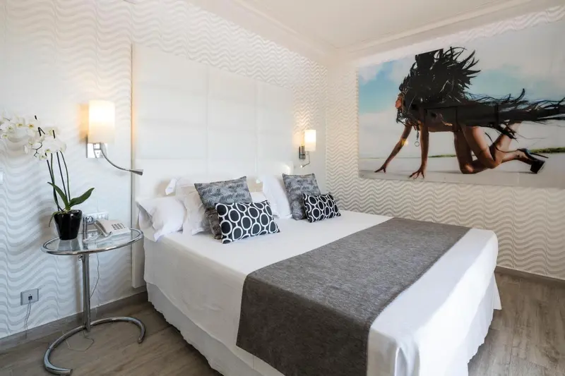 Une chambre lumineuse avec un grand lit et une décoration murale moderne.