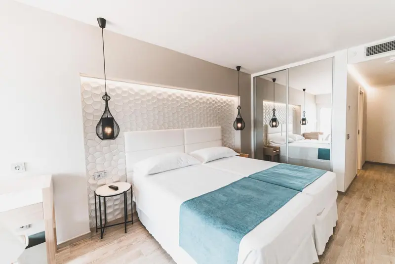 Une chambre lumineuse avec un grand lit et un mur texturé.