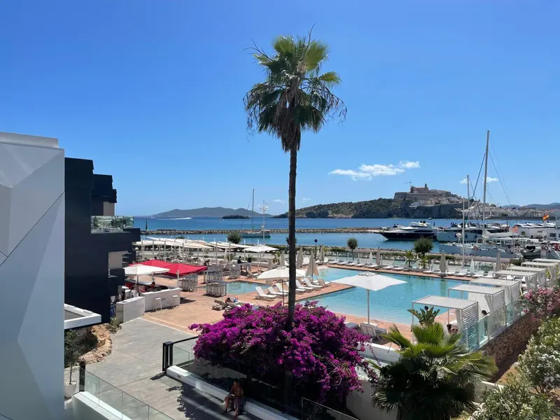 Vue aérienne sur un port de plaisance avec piscine et végétation luxuriante.