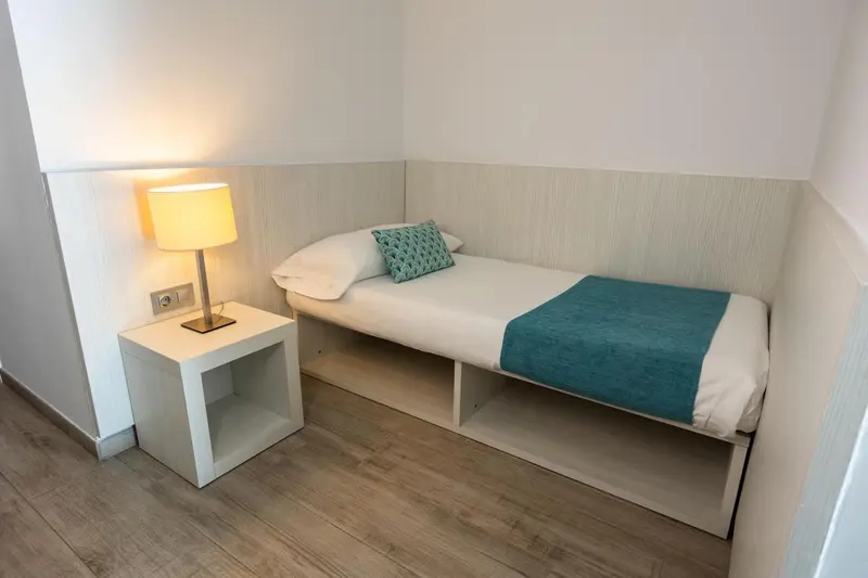 Une chambre lumineuse avec un lit simple et une table de chevet.