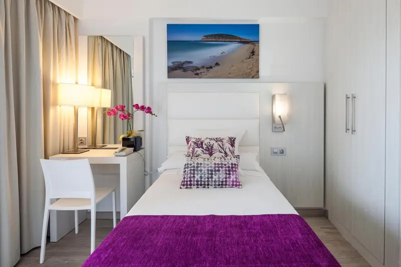 Une chambre lumineuse avec un lit violet et un bureau blanc.