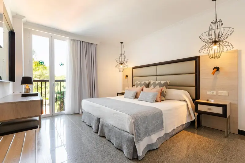 Une chambre lumineuse avec un grand lit et un accès à un balcon.