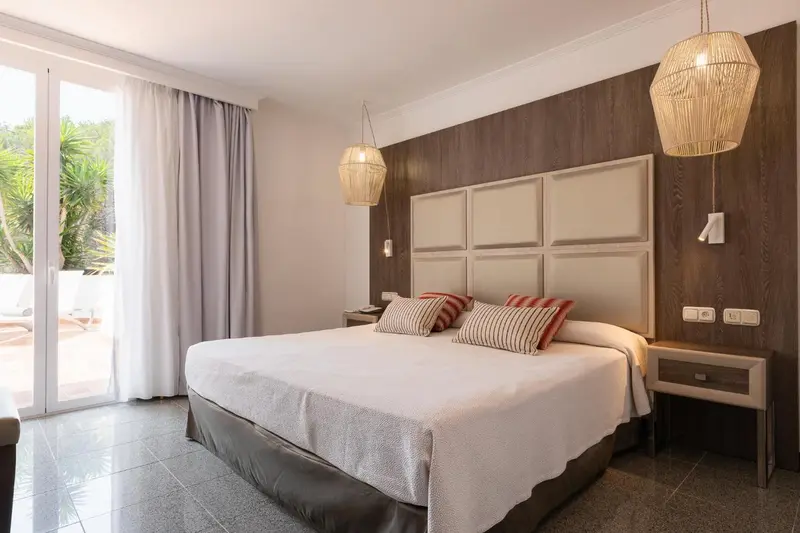 Une chambre lumineuse avec un grand lit et un accès à une terrasse.