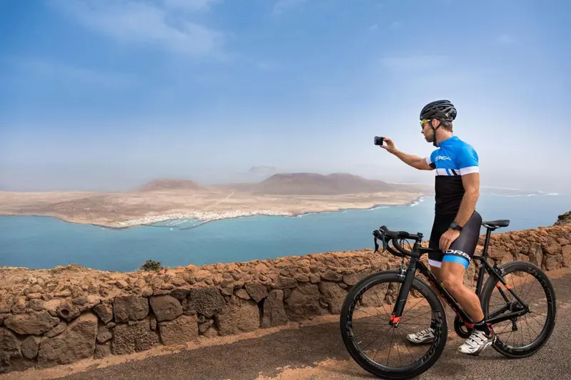 Un cycliste filme un paysage côtier ensoleillé avec son téléphone.