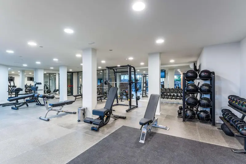Une salle de sport lumineuse avec des équipements de musculation et des miroirs.