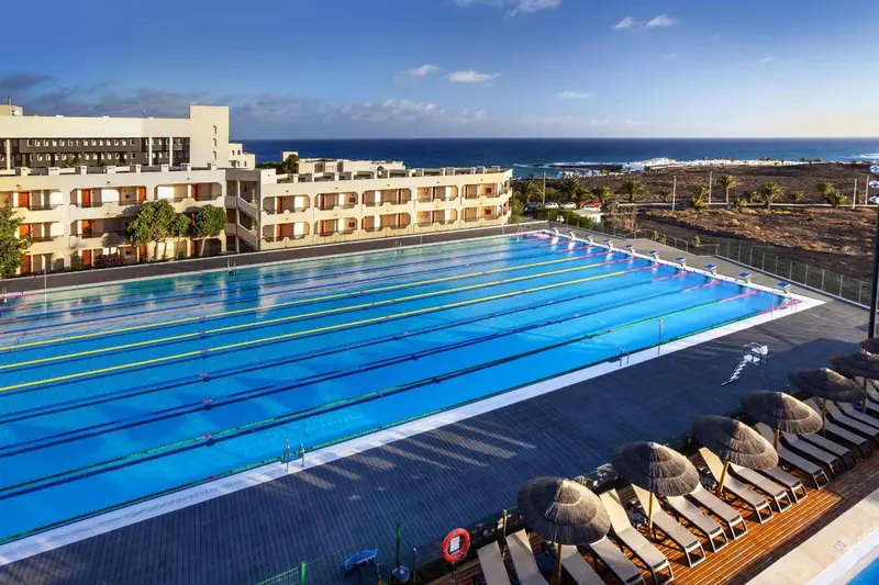 Vue aérienne d'une piscine d'hôtel avec des transats et des parasols.