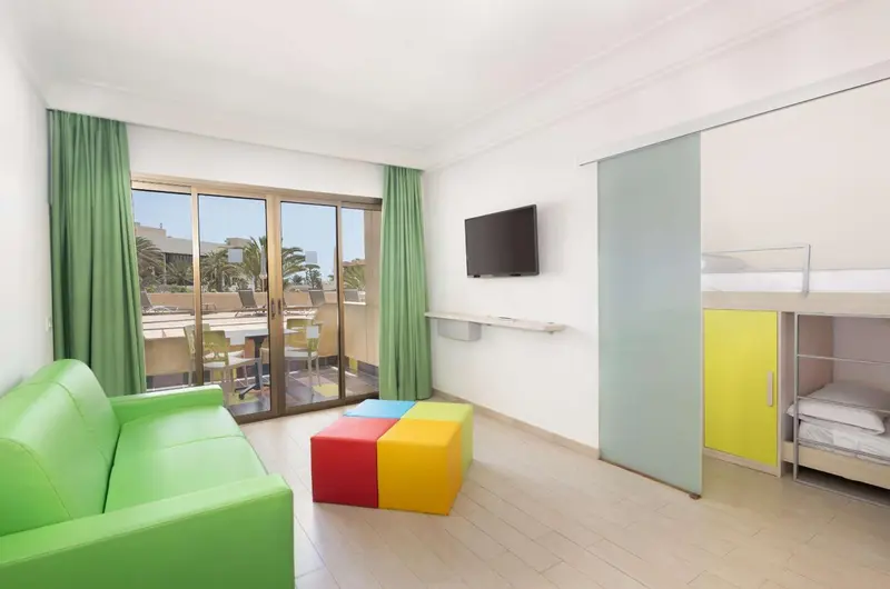 Interieur lumineux d'un logement avec canape vert et lit superpose.
