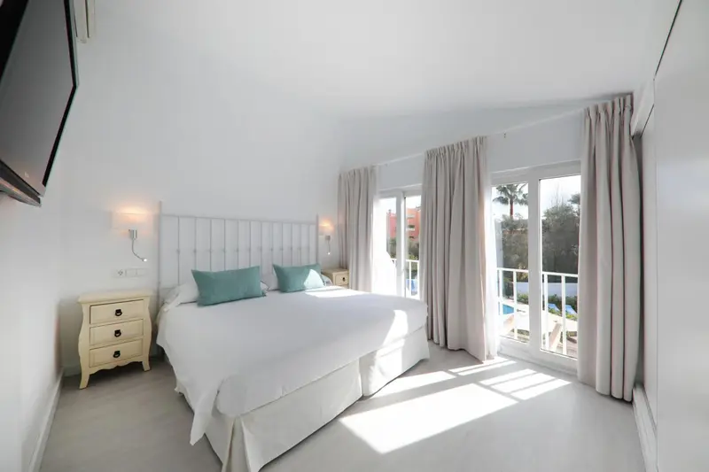 Une chambre lumineuse avec un grand lit et des rideaux clairs.