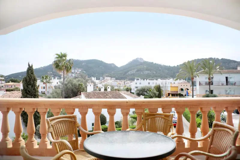Vue sur un paysage urbain et montagneux depuis une terrasse avec mobilier.