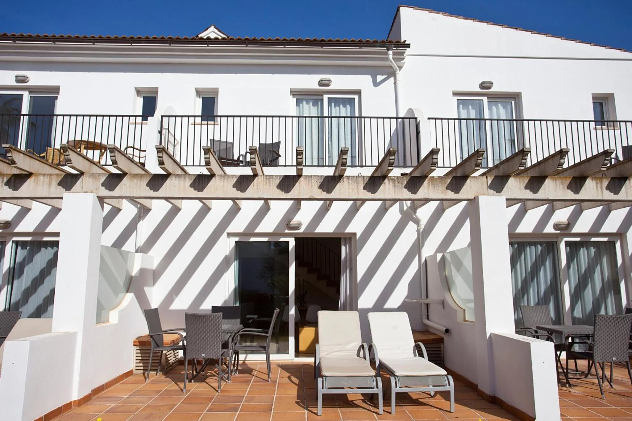Terrasse ombragée avec mobilier de détente et vue sur des logements.