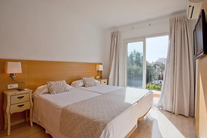 Une chambre lumineuse avec un lit double et un accès à une terrasse.