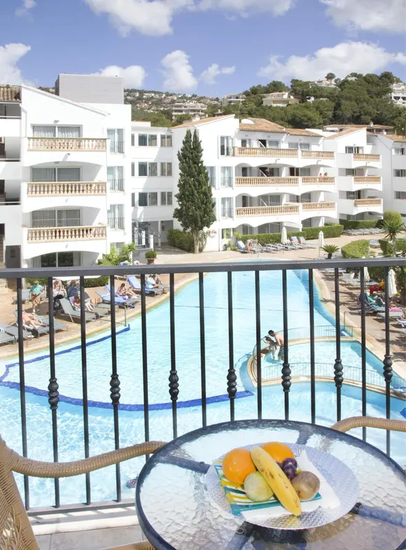 Une vue sur une piscine depuis un balcon avec une table de fruits.