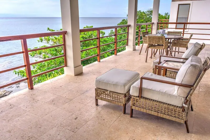 Terrasse aménagée avec mobilier de jardin et vue sur la mer.