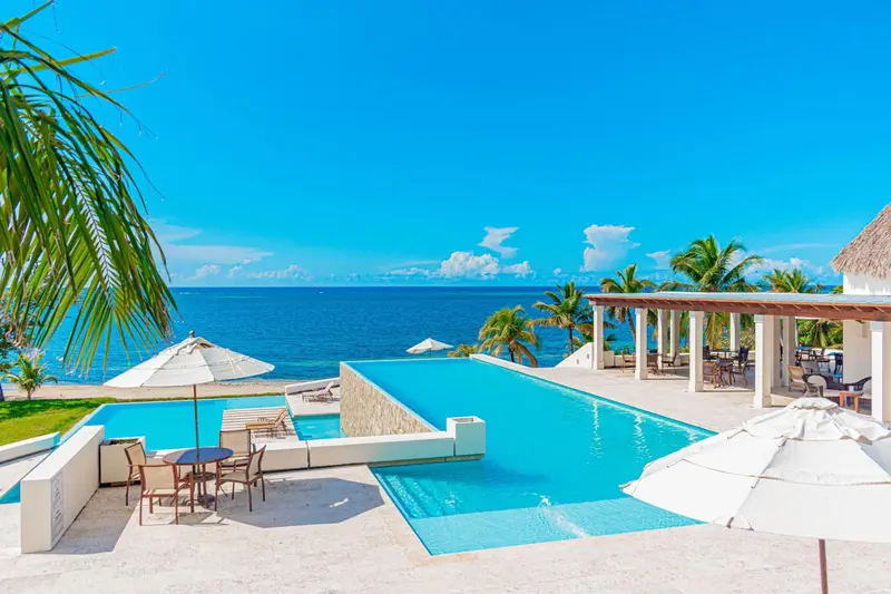 Une piscine à débordement surplombe la mer sous un ciel bleu.
