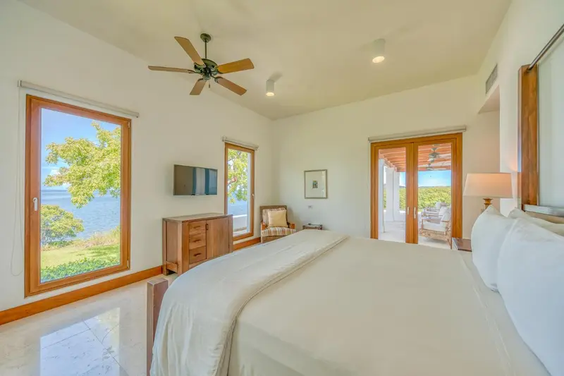 Chambre lumineuse avec un grand lit et vue sur la mer.