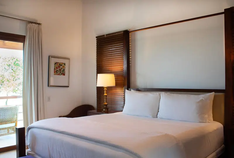 Une chambre lumineuse avec un grand lit et une vue sur l'extérieur.