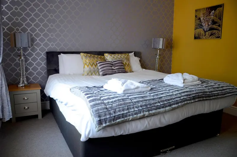 Une chambre lumineuse avec un grand lit recouvert d'une couverture et de coussins.