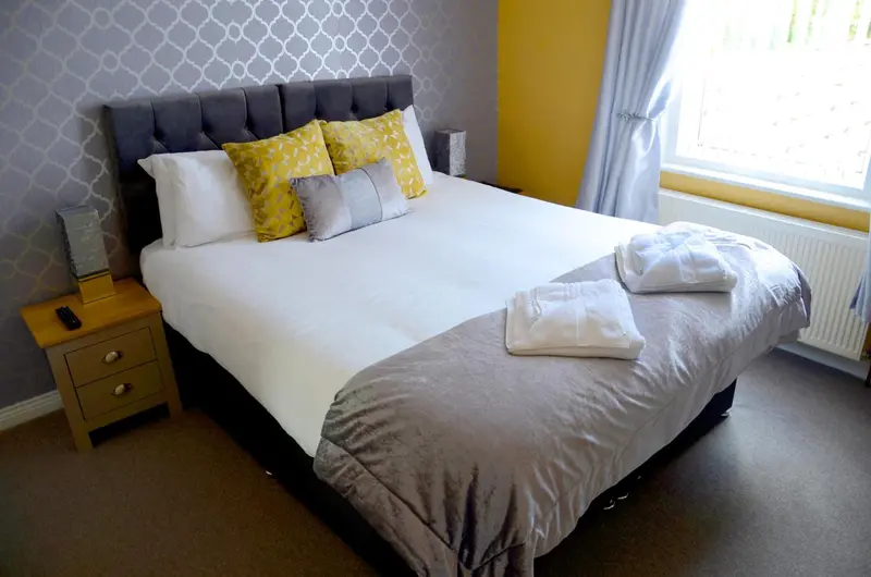 Une chambre lumineuse avec un grand lit recouvert d'oreillers colorés et de couvertures.