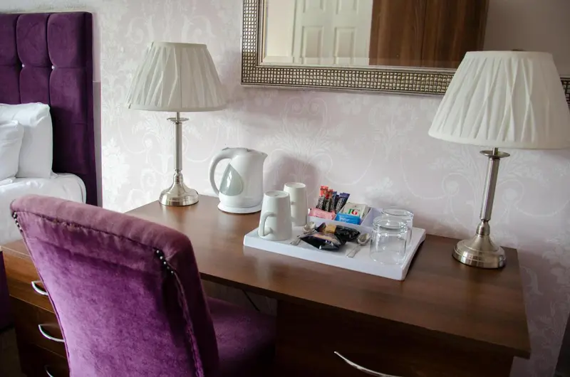 Une table de chevet avec lampes et plateau de courtoisie dans une chambre.