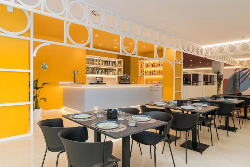 Une salle lumineuse avec des tables dressées pour un repas.