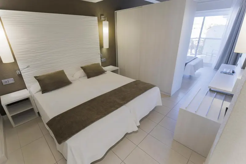 Une chambre lumineuse avec un grand lit et un bureau.