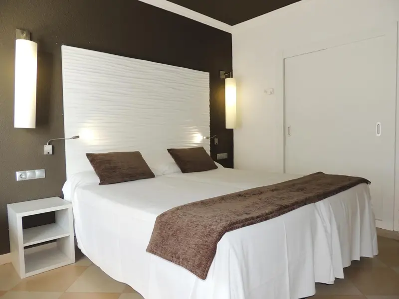 Une chambre lumineuse avec un grand lit recouvert d'une courtepointe.
