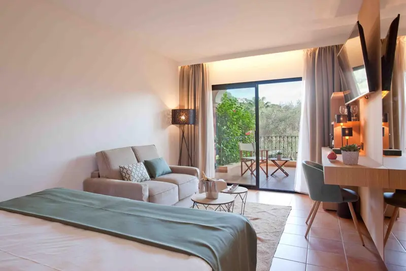 Une chambre lumineuse avec un canapé et un accès à un balcon.