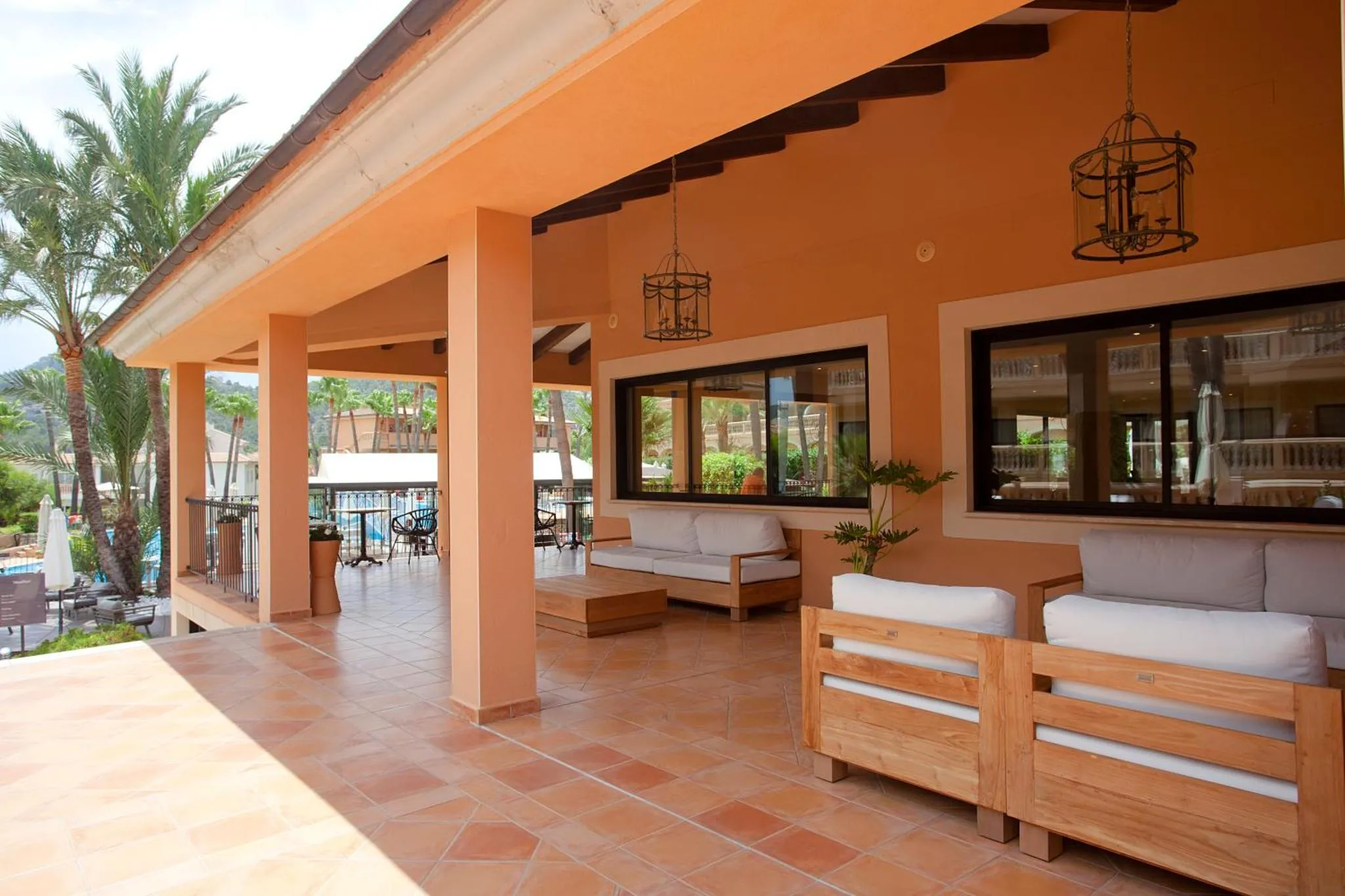 Terrasse ombragée avec mobilier de détente et vue sur un jardin.