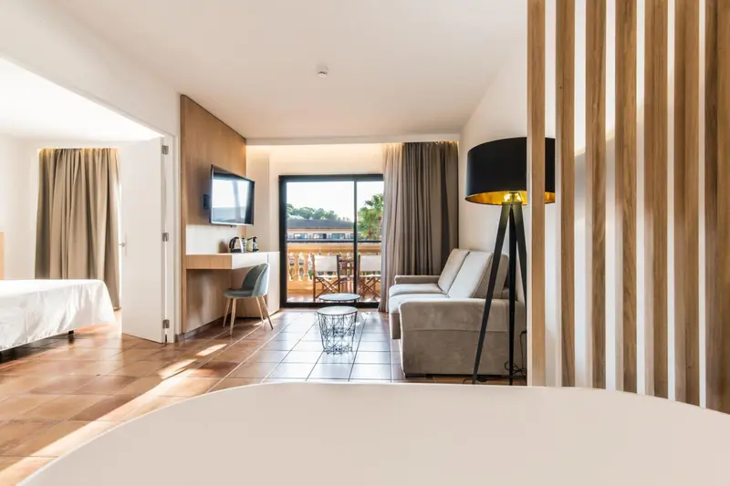 Espace de vie lumineux avec canapé, télévision et accès à une terrasse.