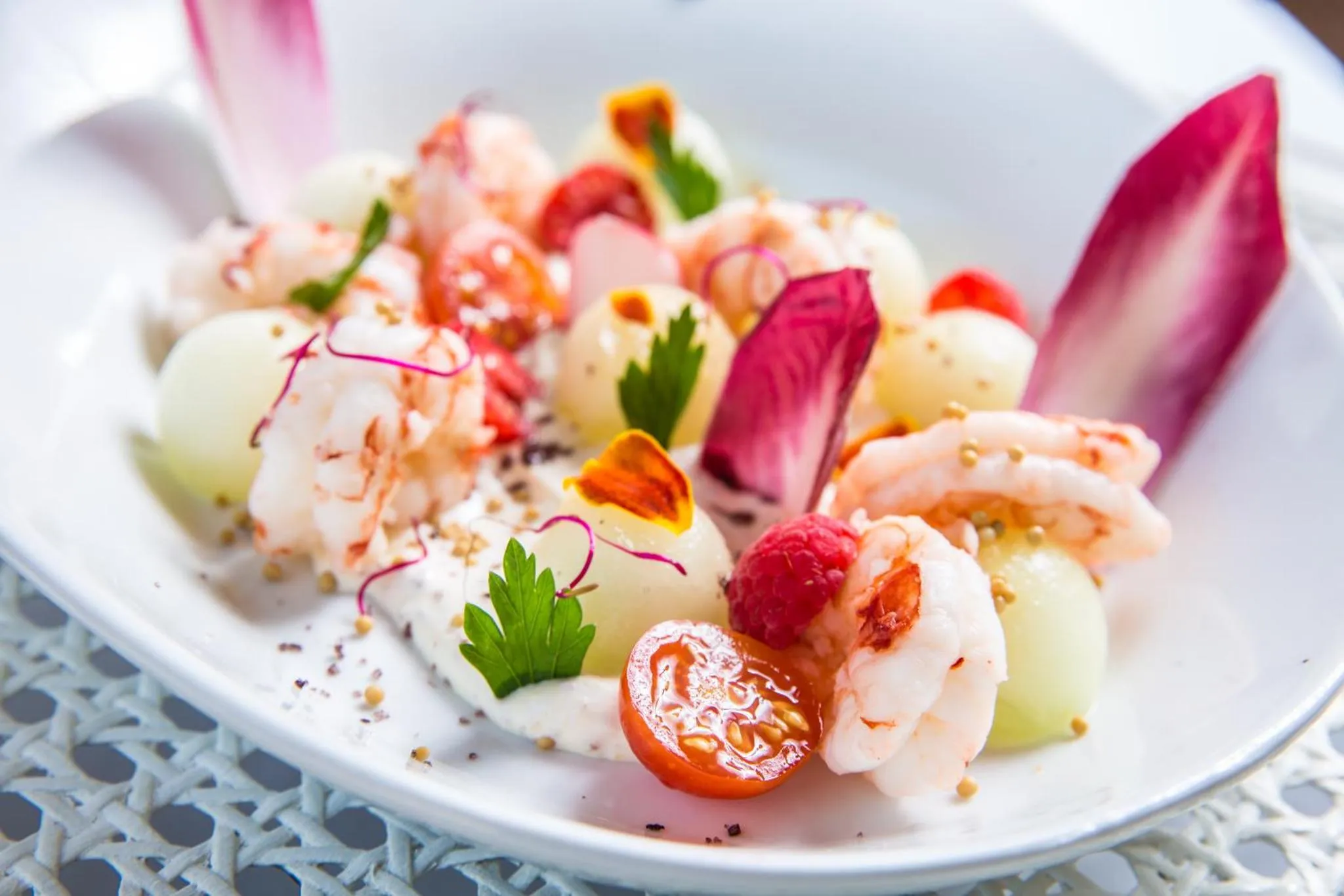 Assiette de salade de crevettes et de fruits frais décorée de verdure et de fleurs.