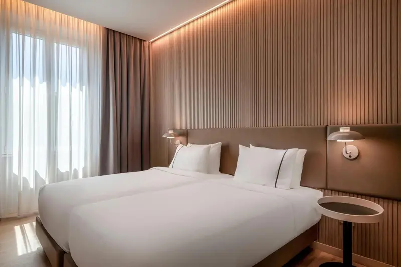 Une chambre lumineuse avec un grand lit recouvert de draps blancs.
